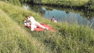 Nudist beach. Public nudity. Sexy MILF without panties and bra sunbathes naked is not shy about fisherman. Naked in public. Milf