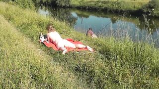 Nudist beach. Public nudity. Sexy MILF without panties and bra sunbathes naked is not shy about fisherman. Naked in public. Milf