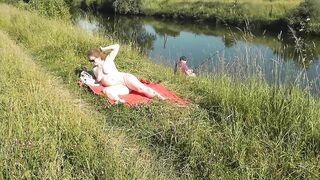 Nudist beach. Public nudity. Sexy MILF without panties and bra sunbathes naked is not shy about fisherman. Naked in public. Milf